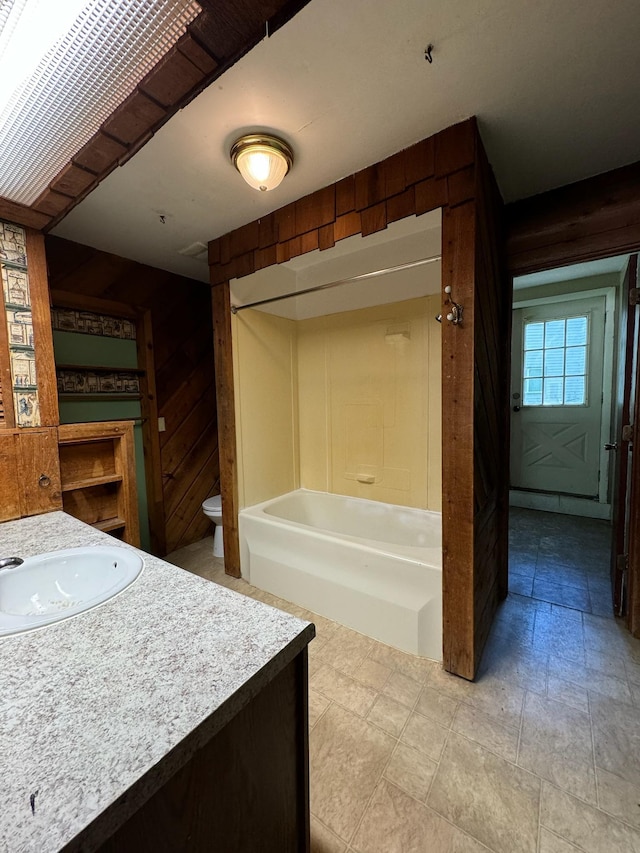 full bathroom with toilet, shower / bath combination, vanity, and wooden walls