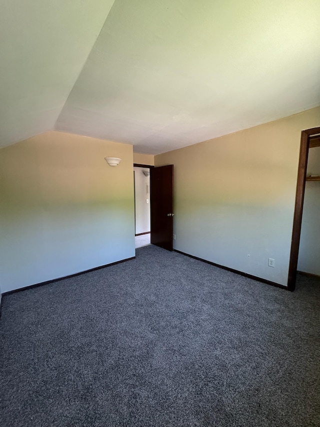 unfurnished room featuring carpet, lofted ceiling, and baseboards