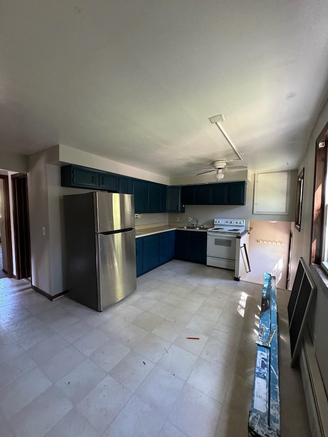 kitchen with a sink, a ceiling fan, electric stove, light countertops, and freestanding refrigerator