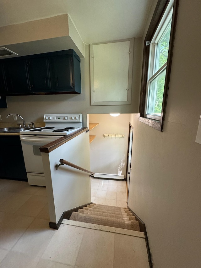 kitchen featuring white electric range, dark cabinetry, light tile patterned flooring, and a sink