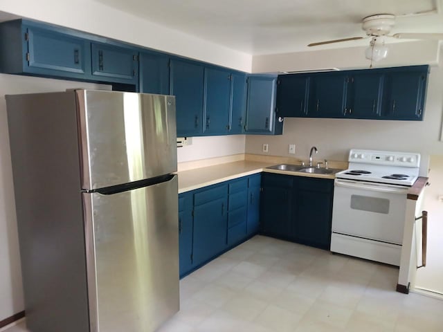 kitchen with freestanding refrigerator, white electric range, a sink, and blue cabinetry