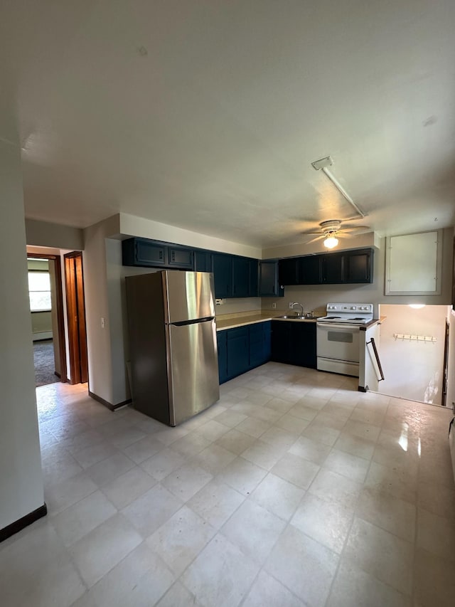 kitchen featuring white electric range oven, baseboards, freestanding refrigerator, light countertops, and a sink