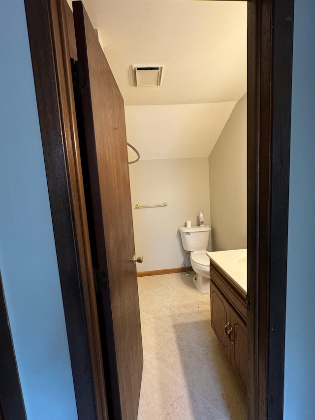 bathroom featuring visible vents, toilet, vaulted ceiling, vanity, and baseboards