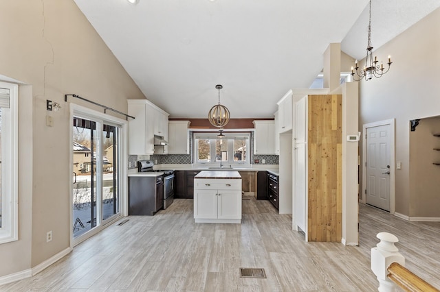 kitchen with an inviting chandelier, a kitchen island, light countertops, and gas stove