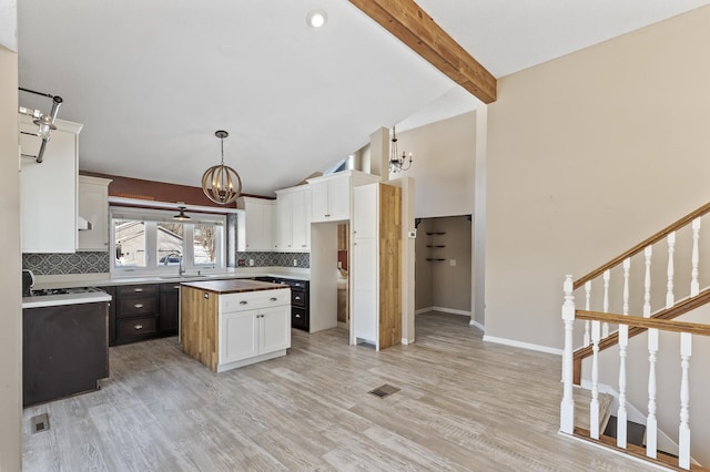 kitchen featuring white cabinetry, visible vents, backsplash, a center island, and an inviting chandelier