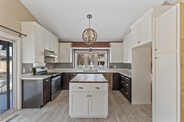 kitchen featuring white cabinets, a kitchen island, under cabinet range hood, pendant lighting, and stainless steel range with gas stovetop