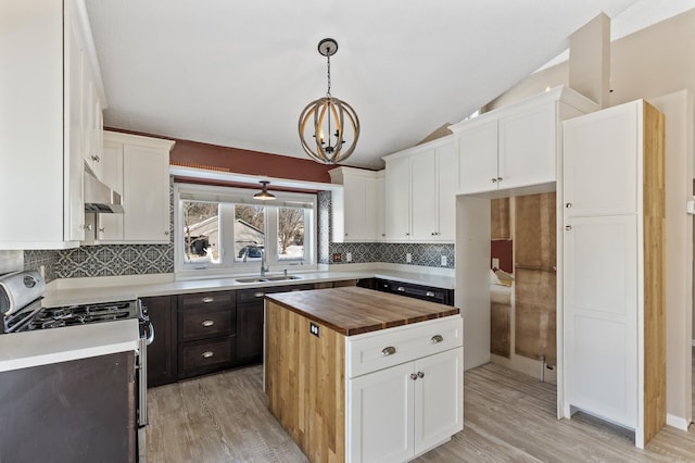 kitchen featuring pendant lighting, white cabinets, under cabinet range hood, and gas range