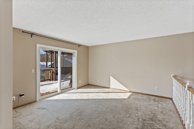 empty room with baseboards, a textured ceiling, and light colored carpet