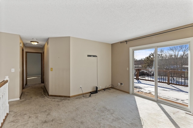 unfurnished room featuring light carpet, a textured ceiling, and baseboards