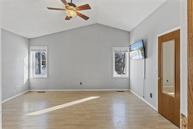 spare room with light wood-style flooring, a wealth of natural light, ceiling fan, and lofted ceiling