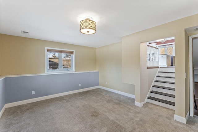 spare room featuring a wealth of natural light, light colored carpet, visible vents, and baseboards