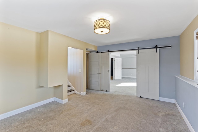 interior space featuring light carpet, a barn door, stairs, and baseboards