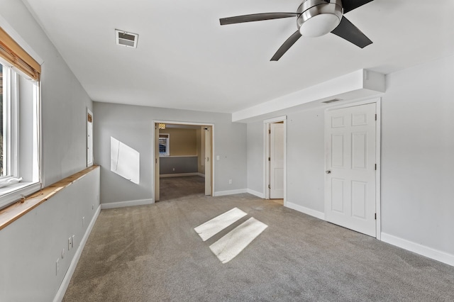 unfurnished bedroom with baseboards, ceiling fan, visible vents, and light colored carpet