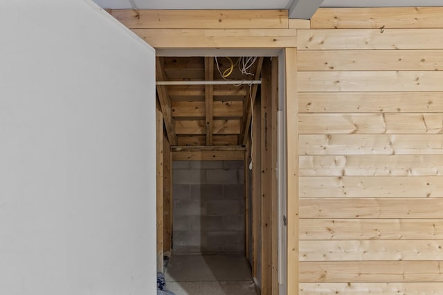 hallway featuring concrete block wall and wooden walls