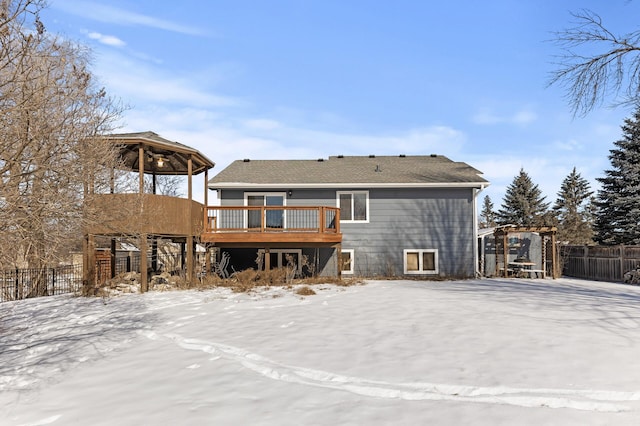 snow covered rear of property with a wooden deck, fence, and a gazebo