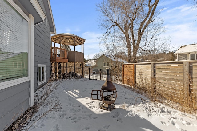 snow covered patio featuring an outdoor fire pit and fence