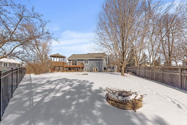 snow covered property featuring a fire pit, a deck, and a fenced backyard