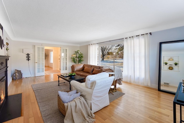 living room featuring light wood-type flooring, french doors, and a textured ceiling