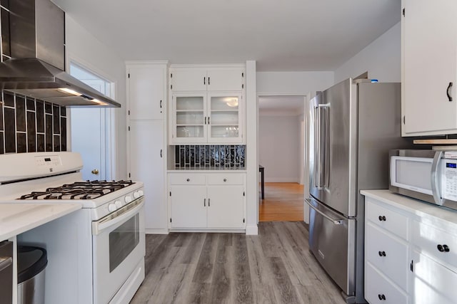 kitchen with white cabinets, white appliances, exhaust hood, and light hardwood / wood-style flooring