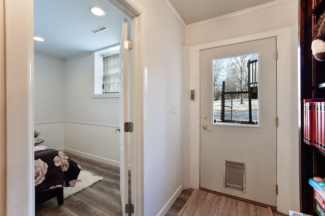 doorway with ornamental molding, a wealth of natural light, and hardwood / wood-style floors