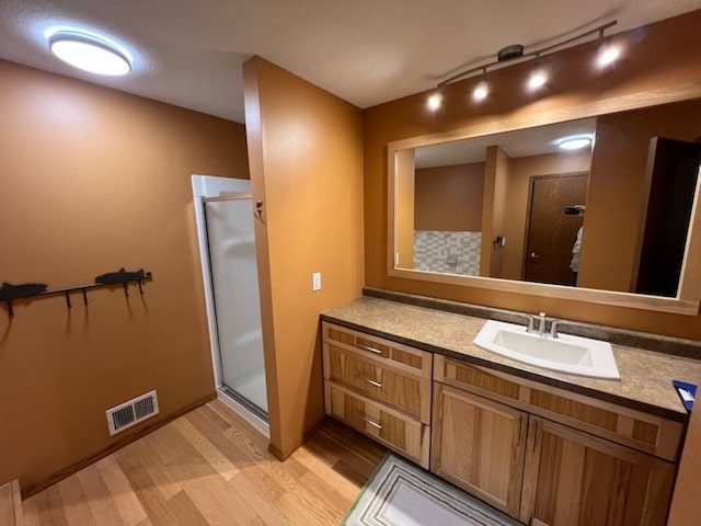 full bathroom with visible vents, a shower stall, vanity, and wood finished floors