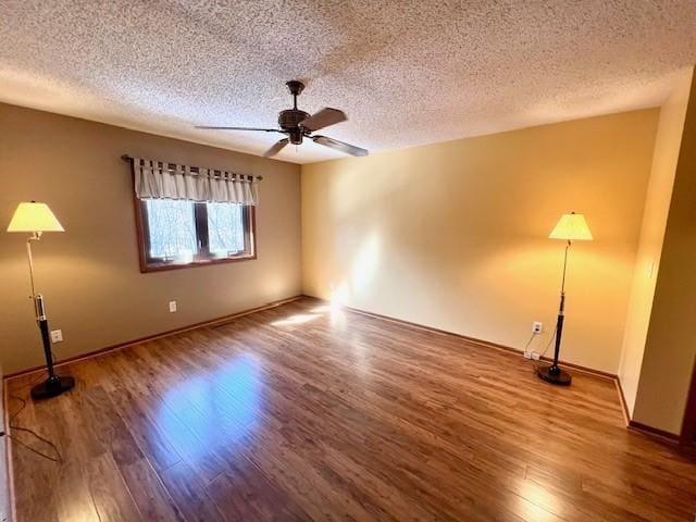 interior space featuring a textured ceiling, wood finished floors, baseboards, and ceiling fan