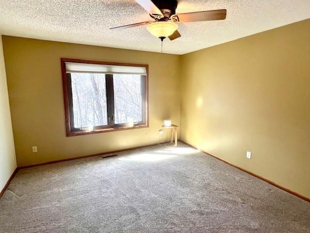 empty room with carpet, baseboards, visible vents, ceiling fan, and a textured ceiling