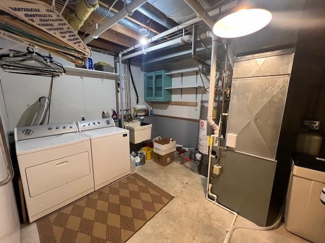 laundry room with a sink, heating unit, gas water heater, laundry area, and washing machine and clothes dryer