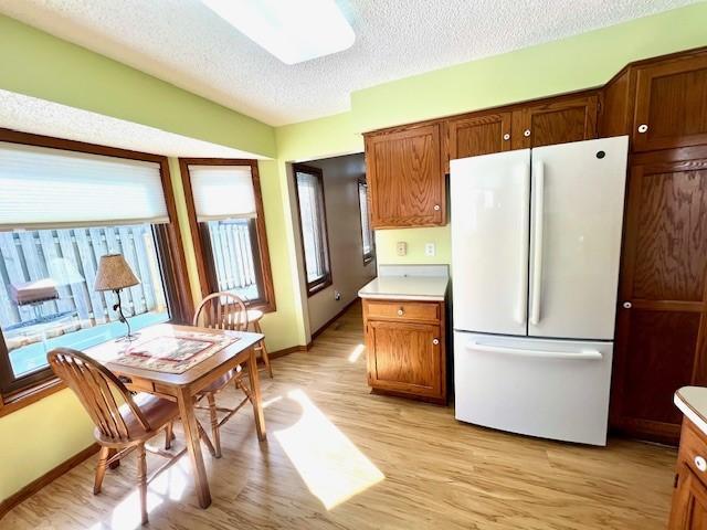 kitchen with a textured ceiling, light wood-style flooring, light countertops, and freestanding refrigerator