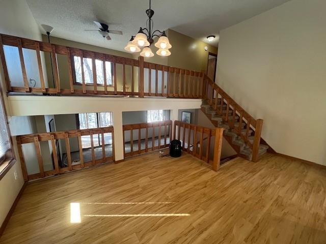 unfurnished living room with stairway, wood finished floors, and a high ceiling