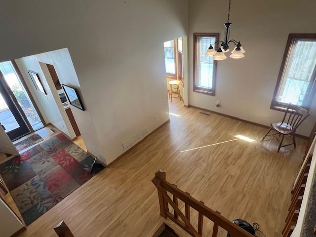 interior space with a chandelier, visible vents, light wood-style flooring, and baseboards