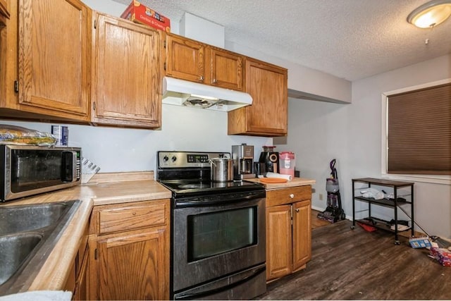 kitchen with appliances with stainless steel finishes, sink, a textured ceiling, and dark hardwood / wood-style flooring