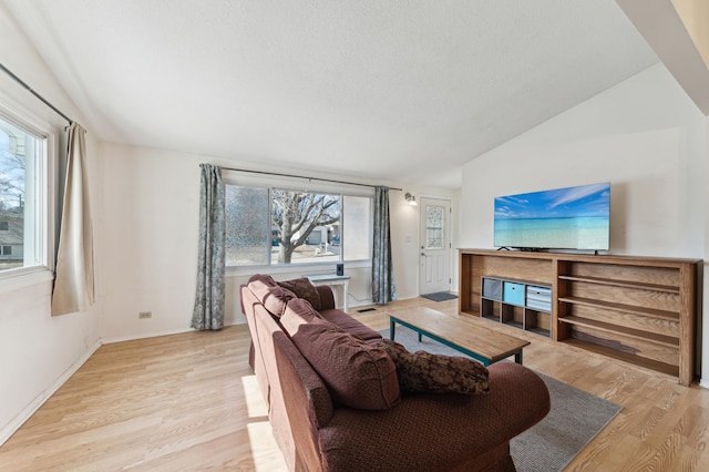 living room with lofted ceiling, light wood-style flooring, and baseboards