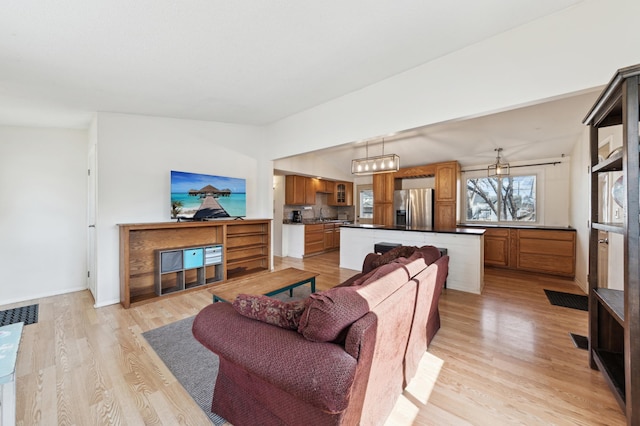 living area with lofted ceiling, light wood-style flooring, and baseboards