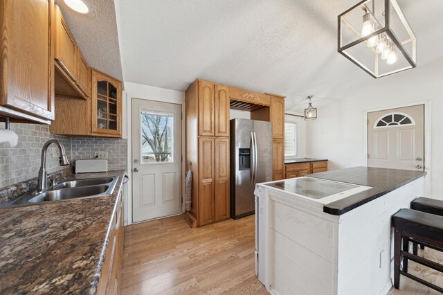 kitchen with dark countertops, light wood-style floors, stainless steel fridge, and a sink