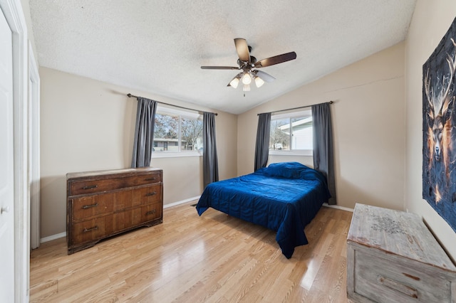 bedroom with baseboards, vaulted ceiling, a textured ceiling, and light wood finished floors