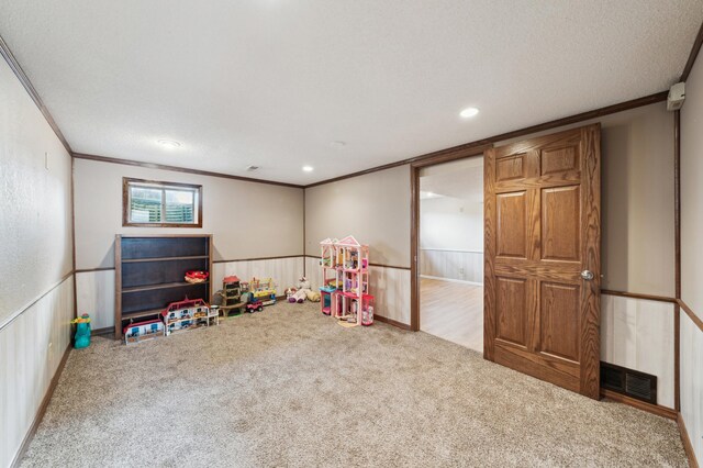 rec room with carpet floors, wainscoting, and crown molding