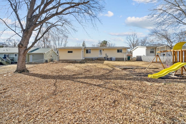 rear view of property with a playground and fence