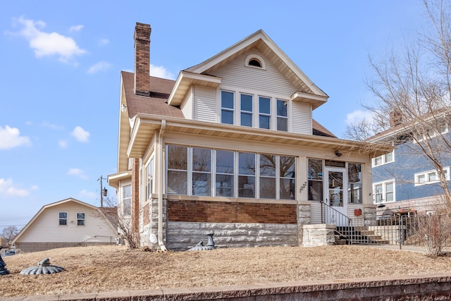 view of front of house with a sunroom, a chimney, and fence