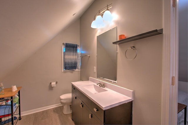 bathroom featuring wood-type flooring, toilet, vaulted ceiling, and vanity