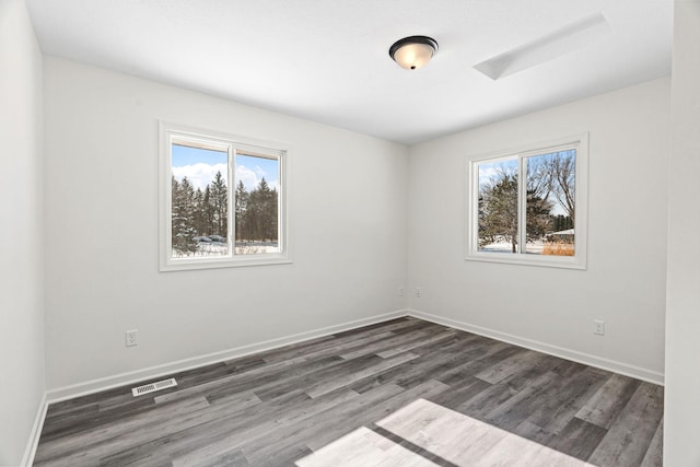 spare room featuring baseboards, plenty of natural light, visible vents, and dark wood-style flooring