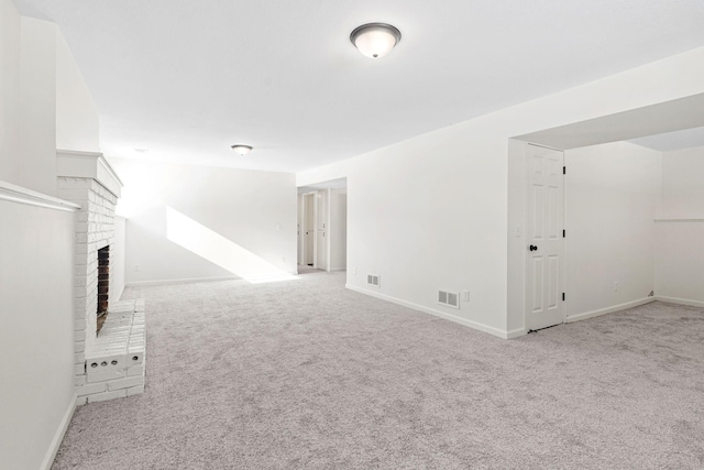 unfurnished living room with light carpet, a brick fireplace, visible vents, and baseboards