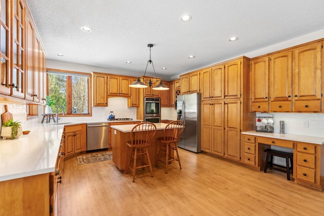 kitchen featuring a sink, a kitchen island, a kitchen breakfast bar, appliances with stainless steel finishes, and pendant lighting