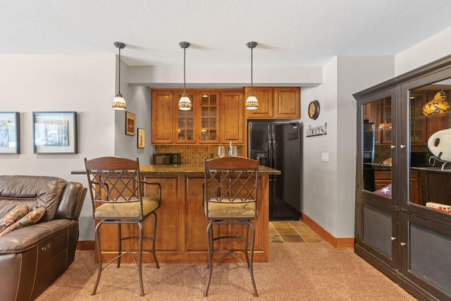 bar with a textured ceiling, light colored carpet, black refrigerator with ice dispenser, decorative light fixtures, and tasteful backsplash