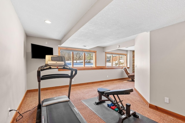 exercise room featuring a textured ceiling, carpet flooring, and baseboards