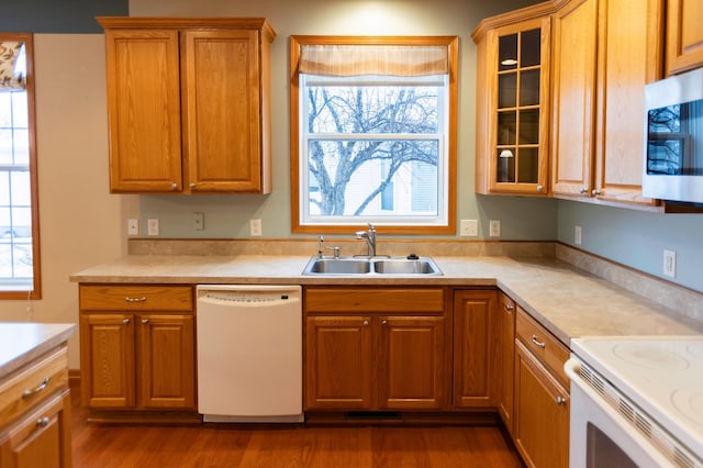 kitchen featuring light countertops, dark wood-type flooring, glass insert cabinets, a sink, and white appliances