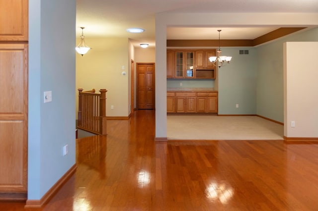 interior space with baseboards, glass insert cabinets, visible vents, and light wood-style floors