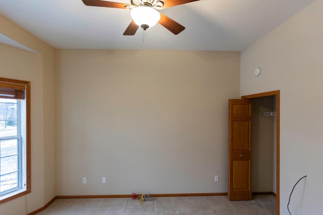 empty room with baseboards, ceiling fan, and light colored carpet