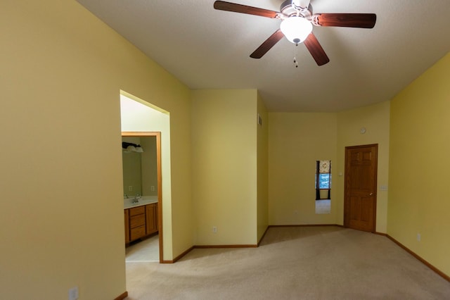 empty room with a ceiling fan, light colored carpet, a sink, and baseboards