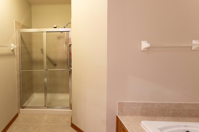 bathroom with a stall shower, baseboards, and tile patterned floors